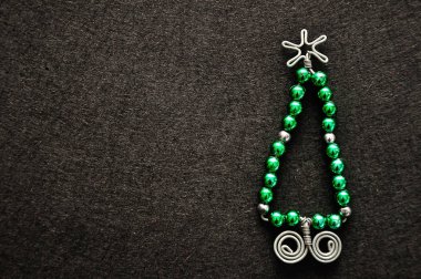 Boncuk ve tel siyah bir zemin üzerine yapılmış bir Noel ağacı