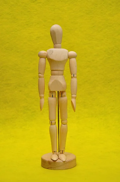 黄色の背景に木製のマネキン — ストック写真