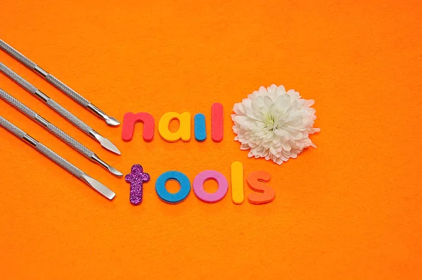 A set of nail tools and a white aster on an orange background and the word nail tools