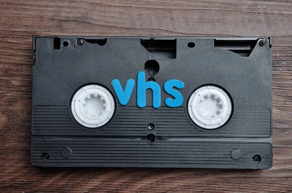 在木制背景上用 "Vhs" 这个词隔离的录像带 — 图库照片