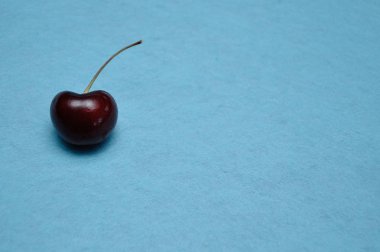 Mavi arka planda tek bir kırmızı kiraz