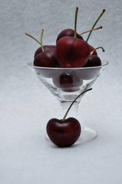 Beyaz arka planda bir cam kase kiraz