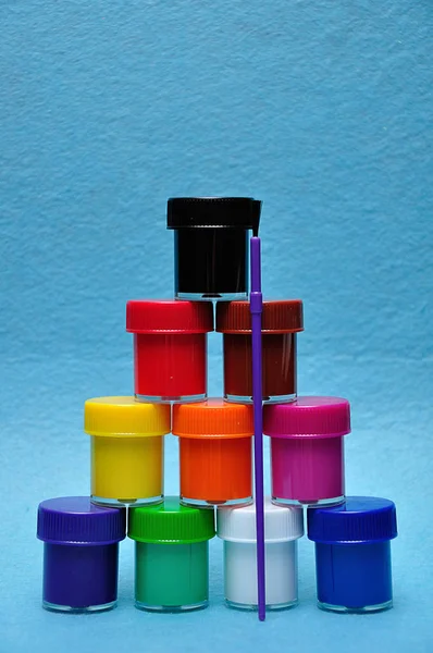 Uma torre de tintas de cores diferentes com um pincel de pintura — Fotografia de Stock
