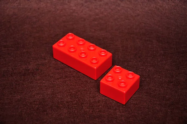 갈색 배경에 두 개의 서로 다른 크기의 빨간색 빌딩 블록 — 스톡 사진
