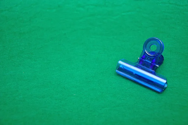 Niebieski plastikowy klip Bulldog na zielonym tle — Zdjęcie stockowe