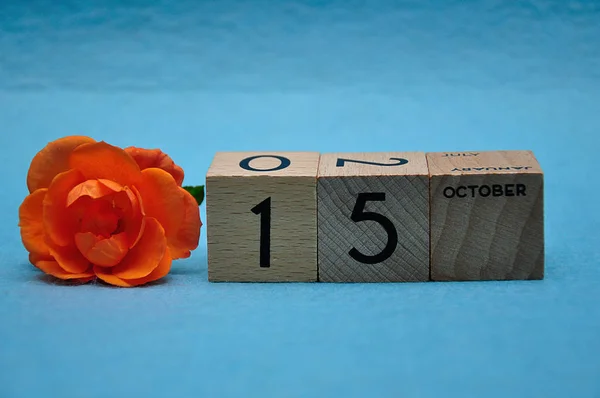 15 октября на деревянных блоках с оранжевой розой на синем фоне — стоковое фото