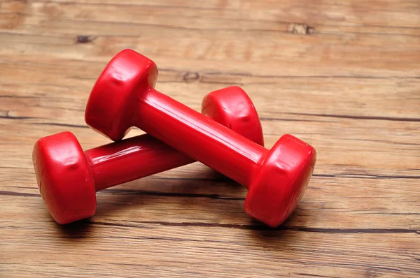 Red dumbbells on a wooden background