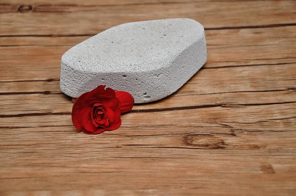 Una piedra abrasiva para eliminar la piel seca del talón con una flor roja — Foto de Stock