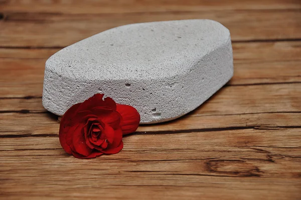 Абразивный камень для удаления сухой кожи с пятки красным цветком — стоковое фото