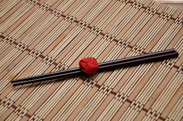 Un par de palillos rojos atados en una alfombra de bambú —  Fotos de Stock