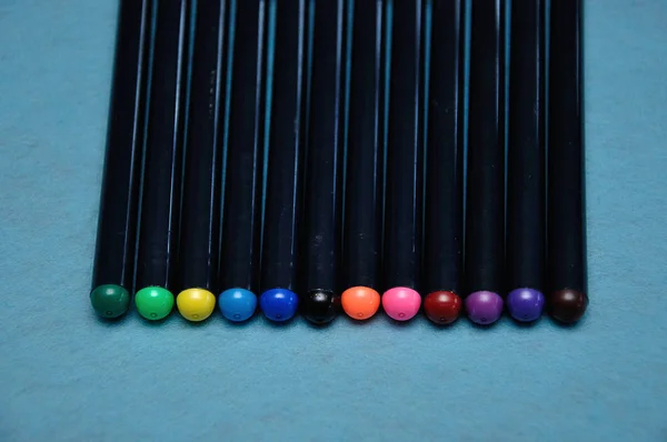 Uma variedade de canetas coloridas em um fundo azul — Fotografia de Stock