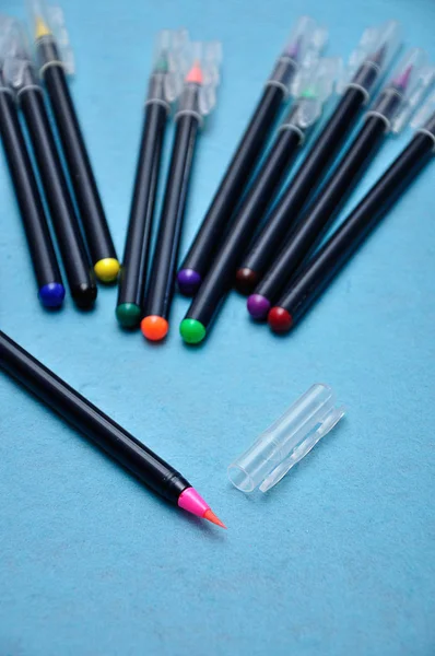 Uma caneta de cor rosa com o resto fora de foco em um fundo azul — Fotografia de Stock
