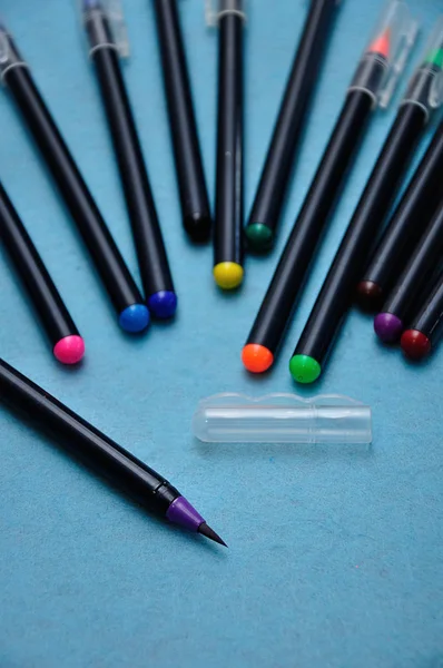 Μια μοβ έγχρωμη πένα με τα υπόλοιπα εκτός εστίασης σε μπλε φόντο — Φωτογραφία Αρχείου