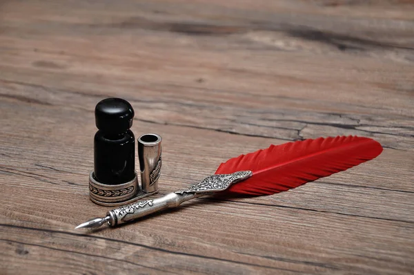 Una pluma vieja con una botella de tinta sobre una mesa de madera — Foto de Stock