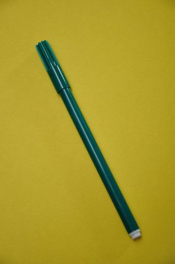 Sarı arka planda izole edilmiş yeşil bir kalem.