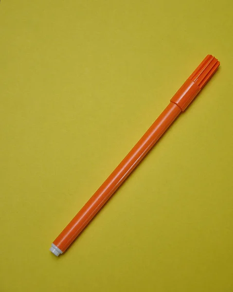 Una pluma naranja aislada sobre un fondo amarillo —  Fotos de Stock