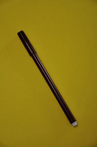 노란 배경에 분리되어 있는 갈색 펜 — 스톡 사진