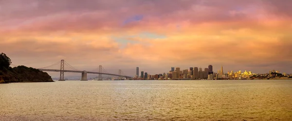 サンフランシスコの街のスカイラインや夕日のパノラマの中にオークランド ブリッジ — ストック写真