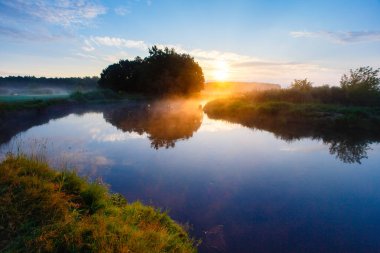 Yaz huzurlu gündoğumu Nehri üzerindeki sis kaplı. Yukarıda sakin kırsal mavi gökyüzü