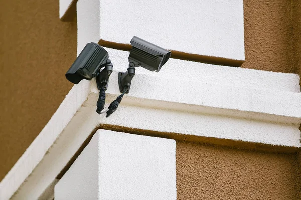 Two CCTV black cameras on building corner