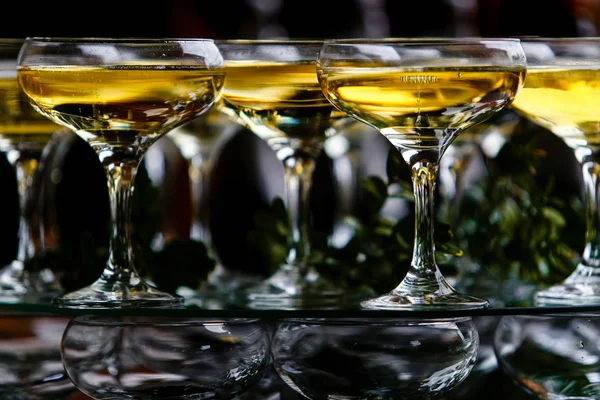 Wine glasses poured with sparkling drink at party macro