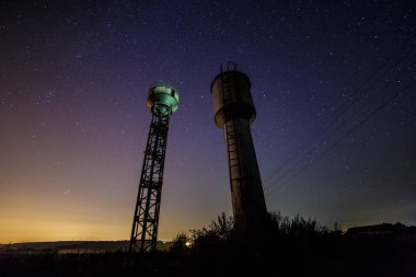 Kırsal kesimde yıldızlı gökyüzü alacakaranlıkta. Gece iki su kuleleri