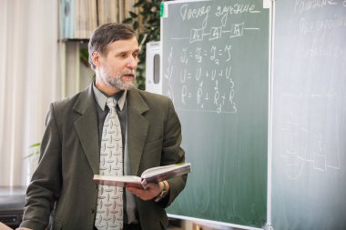 Physicis yazı tahtası, yeni konu açıklayan olgun erkek öğretmen