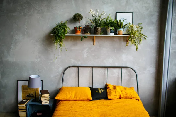 スタイリッシュなベッドルームは、緑の家の植物で装飾。オレンジ色のシーツと枕。インテリアの概念 — ストック写真