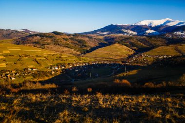Dağlarda erken bahar manzara. Yamaçlarda küçük bir köy. Turizm kavramı