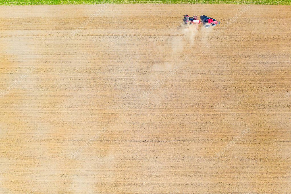 Dry soil background. Rural aerial landscape. Tractor cultivating the farmland