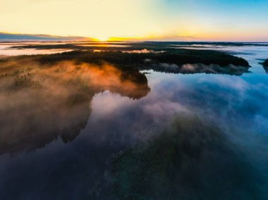 Güneş şafakta ufukta doğar. Göller ve sisteki ormanlar. Hava manzarası