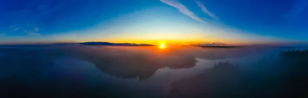 Amazing sun shines on horizon at dawn. Foggy aerial landscape. Blue sky in morning — Stok fotoğraf