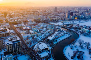 Soğuk kış gününde Minsk şehrinin üzerinde güneş parlıyor, hava manzarası. Nehir donar