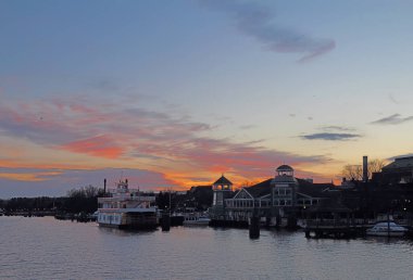 Boats, city skyline and waterfront of Alexandria, Virginia viewed from the water at sunset clipart