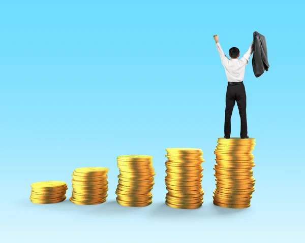 ビジネスマン立って 青い背景上の黄金のコイン スタック上にビジネス金融の成長の成功の概念の背面図 — ストック写真