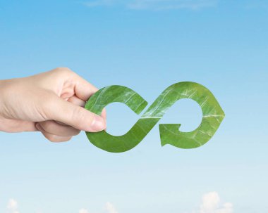 Yeşil Eco-dostça ve dairesel ekonomi kavramı, bir yaprak şekli, mavi gökyüzü arka plan üzerinde geri dönüşüm ok Infinity şeklinde tutan el.