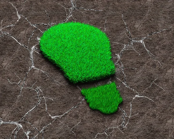 Green grass in the shape of light bulb on dry gray soil with cracks background, concept of ECO and renewable energy.