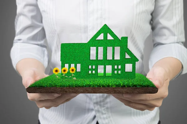 Hände halten grüne Haus auf Gras Land mit Schlamm Sonnenblumen — Stockfoto