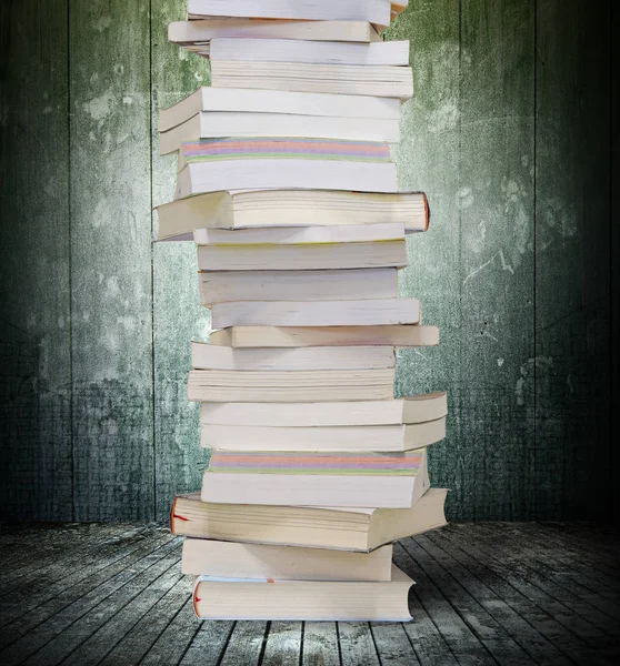 Livros empilhados altos, piso de madeira, fundo de parede de concreto sujo velho — Fotografia de Stock