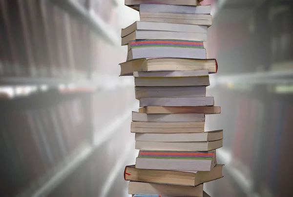 Apilar libros con fondo de estanterías borrosas en la sala de la biblioteca . — Foto de Stock