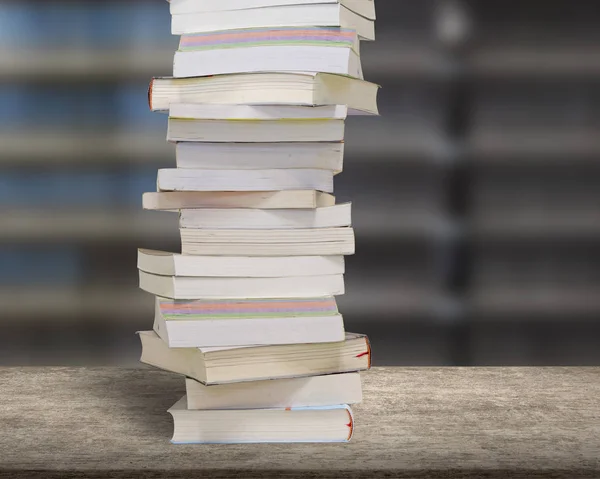 Apilar libros en escritorio de madera con fondo de estanterías borrosas . — Foto de Stock