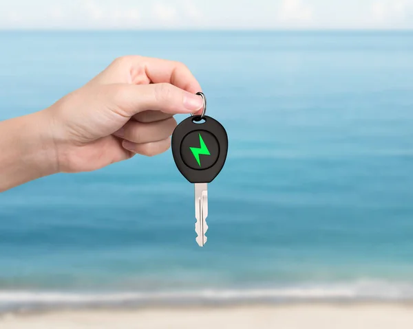 La mano da la llave eléctrica del coche con la muestra verde del perno del relámpago . — Foto de Stock