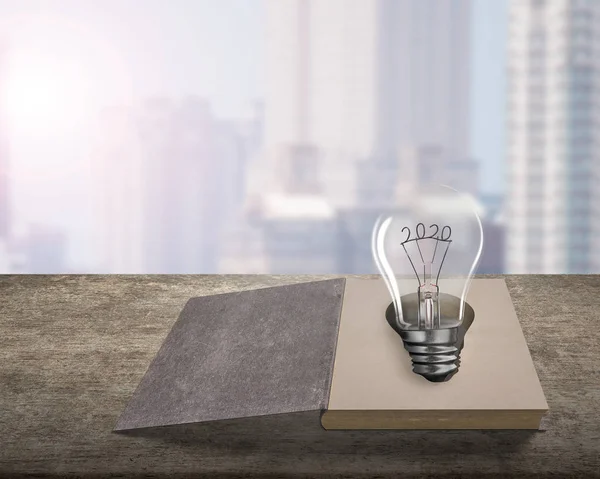 Opened old book with 2020 wire shape of light bulb — Stock Photo, Image