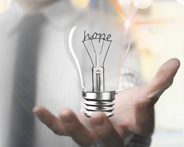 Man palm holding light bulb with hope word wire shapes — Stock Photo, Image