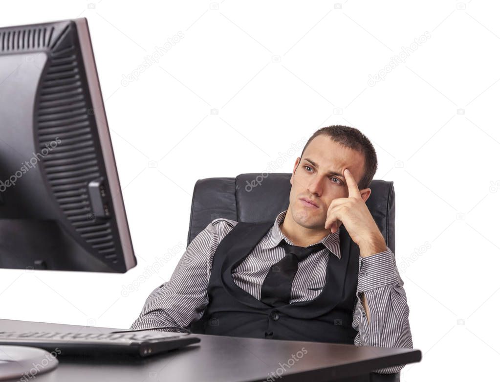 Tired young businessman sitting in front of his computer with a thinking attitude, isolated against a white background.