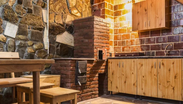 Rustic kitchen with wooden furniture and brick oven in a chalet.