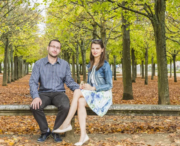 秋の公園の石のベンチに一緒に座っている素敵なカップル — ストック写真