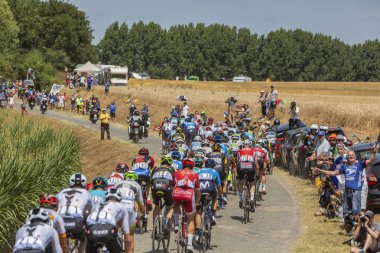 France, Pave Escaudoeuvres Thun - July 15, 2018: Rear view of peloton riding on cobblestone road during stage 9 of Le Tour de FRance 2018 clipart