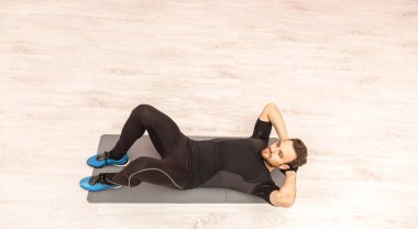 Kuş bakışı bir spor salonunda yerde mekik işi genç bir adam.