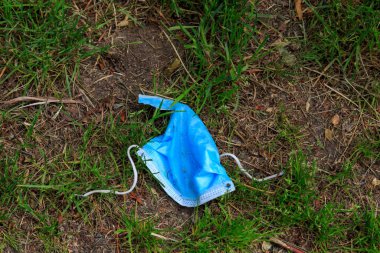 Çimlerin üzerinde cerrahi yüz maskesi..